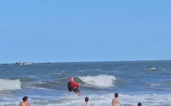 Papai Noel “atrasadinho” vem do mar e distribui balas para a galerinha